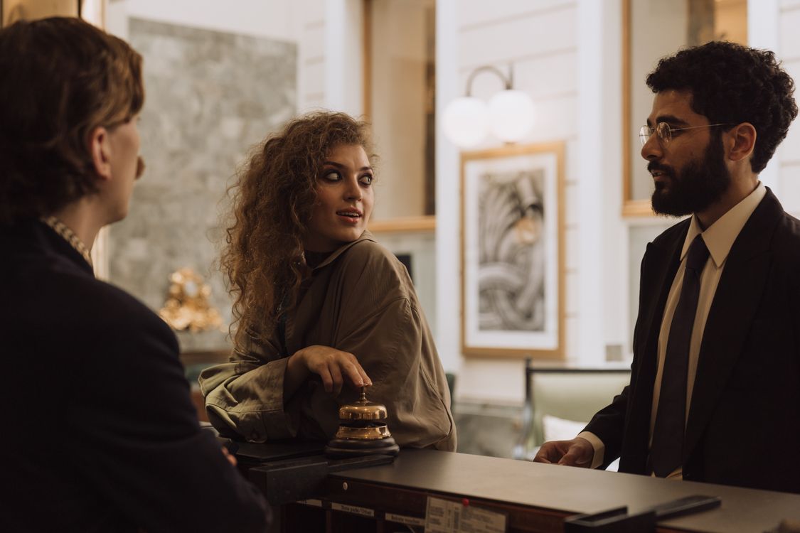 Réceptionniste échangeant avec deux clients au comptoir d’un hôtel