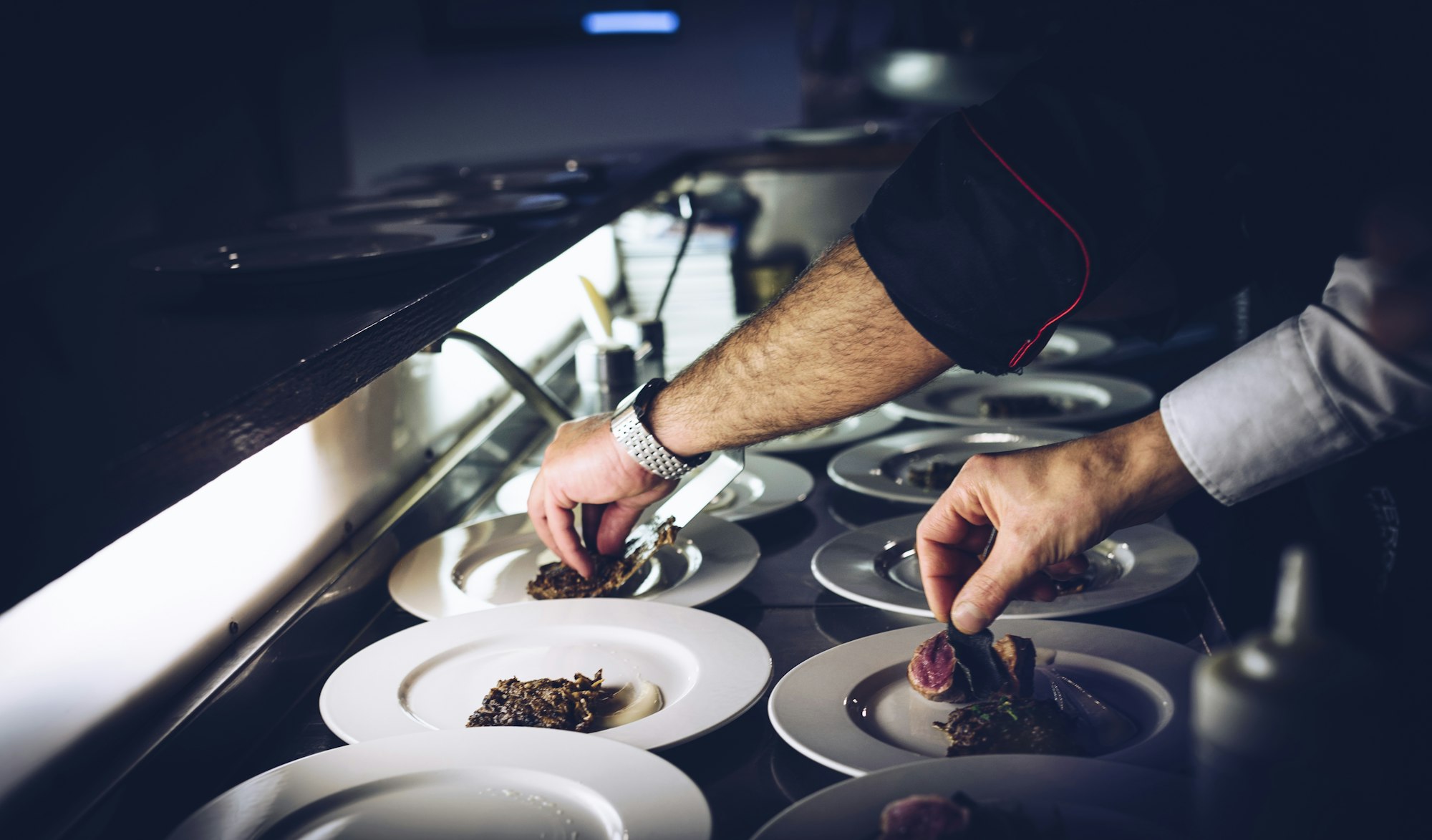 Chef dressant les assiettes au pass d’une cuisine gastronomique