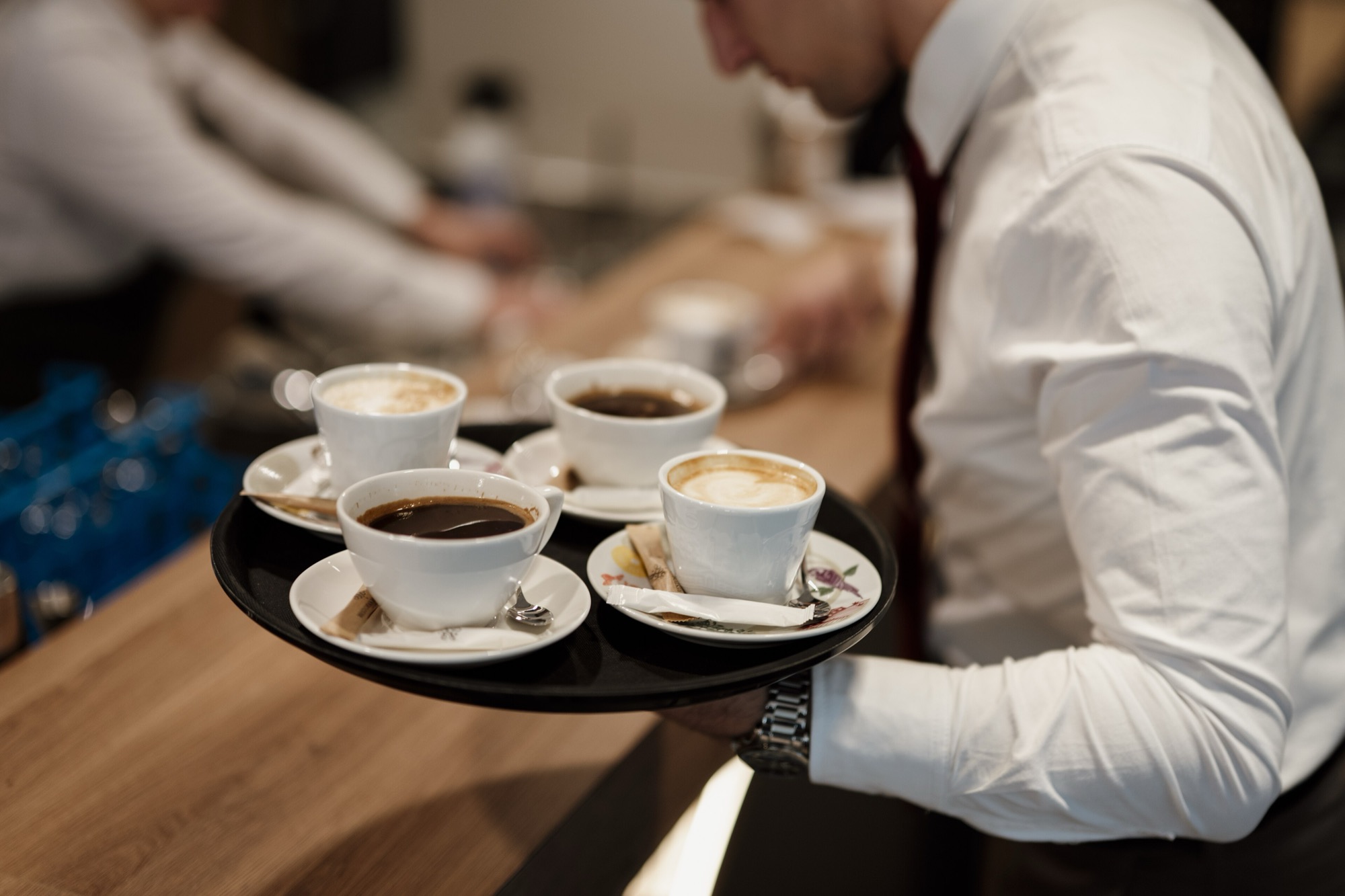 Serveur portant un plateau de cafés pendant le service